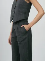 Chaleco sastrero color beige, con escote en V, cierre frontal con botones y bolsillos laterales decorativos.