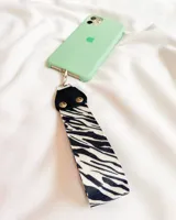 Llavero de tela con estampado de cebra, con detalles en cuero sintético negro y gancho metálico plateado.