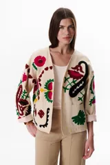 Chaqueta color crudo con bordados florales en tonos rojo, verde y negro.
