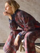 Campera estilo bomber de silueta relajada, confeccionada en una combinación de tela a cuadros en tonos bordó, azul y marrón con detalles de denim oscuro en cuello y puños.