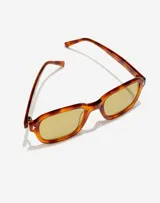 Lentes de sol unisex con armazón de acetato en tono carey y cristales amarillos. Presentan un diseño de marco cuadrado con detalles metálicos en las esquinas y la firma de Manuel Turizo en el interior de la patilla.