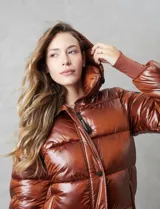 Campera puffer larga de abrigo marca BCBG Maxazria, color beige. Cuenta con capucha desmontable, cuello alto envolvente, cierre frontal bidireccional con solapa de botones a presión, bolsillos laterales, puños internos elastizados y tajos laterales con cierre en el bajo.