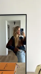 Sweater tejido de lana azul marino y marrón con cuello polo color crema y botones en el frente.