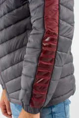 Campera puffer de nylon con relleno de guata, diseño capitoneado y capucha desmontable. Presenta cierre frontal, bolsillos laterales con cierre y detalles en color bordó en mangas y cierres.