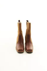 Bota de caña media combinada en cuero liso y descarne color marrón, con punta cuadrada, cierre lateral y taco ancho de madera.