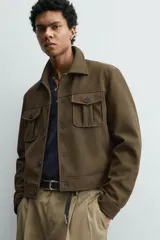 Cazadora cropped fit de efecto piel en color verde militar, con cuello solapa, manga larga con puño abotonado, bolsillos frontales de plastrón con solapa y cierre de botonadura.