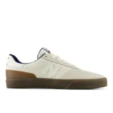 Championes New Balance Numeric 272, diseñados para skate, con parte superior de gamuza y materiales sintéticos en color beige. Presentan suela de goma color marrón, detalles en azul marino y el logo N característico en el lateral.