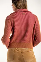 Campera tejida de algodón con diseño acanalado, cuello alto y cierre frontal completo. Presenta un patrón bicolor en tonos terracota y rosado, con puños y cintura elásticos.