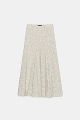 Falda midi fluida de tiro medio en color crudo con estampado de lunares negros, de corte evasé y caída ligera.