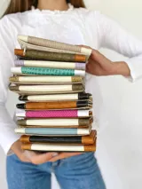 Billetera de cuero con estampado reptil en color marrón y fucsia con detalles en blanco. Tiene un sistema de cierre con broche y monedero externo.