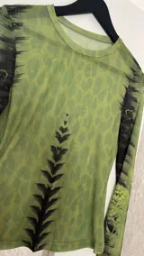 Top de microtul verde con estampado abstracto en tonos verdes y negros, de mangas largas y cuello redondo.