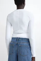 Remera entallada de manga larga y cuello redondo, confeccionada en punto de algodón.