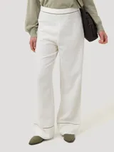 Pantalon de corte recto y tiro alto, confeccionado en una mezcla de lino orgánico y viscosa. Presenta detalles de calado decorativo en la cintura y en el ruedo de las piernas.