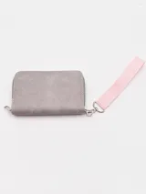 Billetera de mano color gris con textura gamuzada, cierre perimetral y correa de muñeca de tela en color rosado.