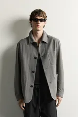 Sobrecamisa gris de corte regular fit con textura, cuello solapa, cierre frontal de botones, bolsillos de parche en el pecho y los laterales, y mangas largas con puños abotonados.