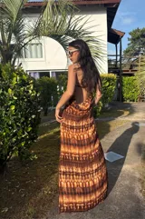 Vestido largo strapless, ajustado al cuerpo, con estampado batik en tonos marrones y naranjas.