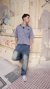 Camisa de corte boxy fit confeccionada en algodón con estampado de cuadros vichy en blanco y negro. Presenta un diseño gráfico artístico en color negro y blanco en la parte posterior.