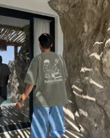 Remera oversize negra con diseño gráfico en la espalda que incluye la inscripción "Kaboa Radio" y un personaje ilustrado, de corte amplio y mangas cortas.