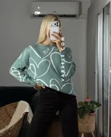 Sweater de tejido de punto con diseño abstracto de líneas blancas sobre fondo de color sólido. Presenta un corte clásico y textura suave.