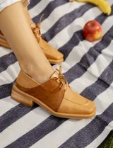 Zapato acordonado de cuero vacuno con diseño bicolor en tonos tostado y marrón, con textura punteada en los laterales y puntera cuadrada.