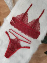 Conjunto de lencería de encaje color rojo, compuesto por un bralette triangular con breteles regulables y una tanga con tiras laterales ajustables.