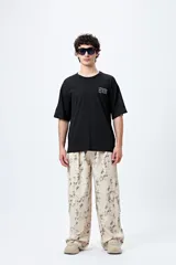 Remera blanca de corte amplio con mangas cortas y estampado con la frase "Unlearn" en el frente y gráfico en la espalda.