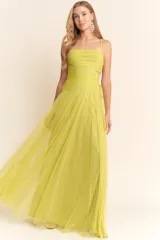 Vestido largo de fiesta color verde lima, confeccionado en tul con diseño de escote recto, breteles finos y detalles cut-out laterales en la cintura. Presenta un cuerpo drapeado y una falda amplia con caída fluida.
