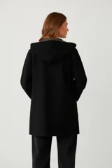 Saco largo de tejido de punto color camel, con capucha y bolsillos frontales. El interior de la capucha y el borde frontal tienen un estampado geométrico en tonos beige y marrón.