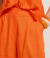 Short de sastre color naranja, de tiro alto con pliegues frontales, bolsillos y ruedo con vuelta. Confeccionado en mezcla de viscosa y lino.