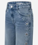 Pantalón wide leg de tiro bajo confeccionado en jean de algodón, con diseño amplio y aplicación de tachas y ojalillos metálicos a lo largo de los laterales.