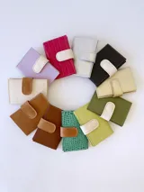 Tarjetero plateado de cuero con broche a presión. Tiene espacio para 4 tarjetas y billetes, y un bolsillo externo.