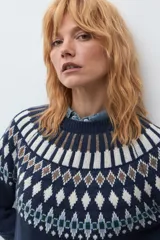 Sweater de punto en color azul marino con diseño jacquard geométrico en tonos blanco, marrón y verde en el canesú, puños y ruedo. Presenta cuello redondo y mangas largas.