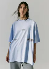 Remerón de corte oversize y manga corta, color celeste, con cuello redondo y estampa gráfica frontal con texto en color marrón.