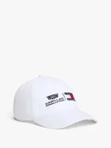 Gorra de béisbol blanca de seis paneles, confeccionada en algodón. Presenta bordados frontales con los logotipos de Cadillac Formula 1 Team y Tommy Hilfiger. Incluye ojales de ventilación, botón superior y hebilla metálica de ajuste en la parte trasera.