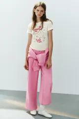 Camiseta blanca de algodón con cuello redondo, manga corta y calce regular. Presenta un estampado frontal ilustrado con conejos, corazones, estrellas y el texto "Kindness for every kind".