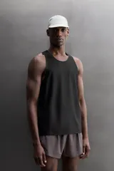 Musculosa deportiva Zara Athleticz de tejido ligero y elástico con paneles laterales de malla transpirable. Presenta cuello redondo, sisas amplias y bajo con aberturas laterales.