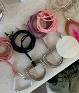 Collar de cordón de gamuza sintética con dije metálico de diseño geométrico o circular. El diseño permite diversas formas de uso, ya sea atado al cuello o con el dije al frente.
