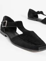Zapato guillermina de cuero con pelo negro, con punta cuadrada, tira sobre el empeine con hebilla metálica y suela plana.