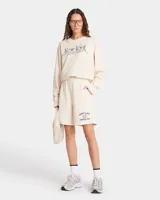 Short color crema de jersey grueso, largo medio, con cintura con cordón, bolsillos delanteros y un bolsillo trasero. Estampado frontal con el logo de la marca.