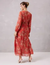 Vestido midi de gasa estampada con diseño floral, escote en V cruzado, cintura elastizada con lazo de ajuste y mangas largas con puños fruncidos. Incluye forro interno a tono.