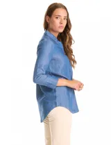 Blusa de lyocell color azul con efecto denim, cuello camisero con solapa y escote en V con cierre de un botón. Presenta mangas tres cuartos con terminación doblada y ruedo redondeado.
