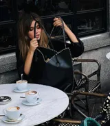 Cartera de cuero color marrón chocolate con manijas largas y borde superior en corte en V. Diseño amplio y liviano, con terminaciones artesanales y costuras contrastantes en todo el contorno.