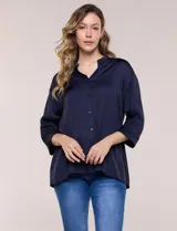 Camisa de satén azul marino con cuello mao, escote en V y mangas tres cuartos con hombro caído. Presenta silueta holgada, cierre frontal con botones y ruedo asimétrico.