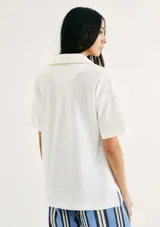 Camiseta blanca de manga corta con cuello polo profundo en V y logo bordado de Hering en el pecho.