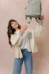 Mochila compacta de color beige, con compartimento principal con cierre, bolsillos laterales y bolsillo frontal con cierre oculto. Cuenta con correas regulables y acolchonadas y asa superior.