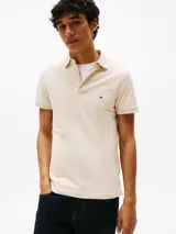 Chomba Tommy Hilfiger color beige, corte slim fit, con cuello clásico, tapeta de dos botones y logo bordado en el pecho.