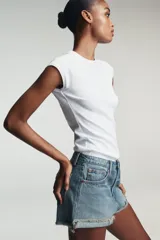 Shorts de jean de algodón, tiro alto, color azul claro desgastado. Presenta cinco bolsillos, cierre frontal con botón metálico y cremallera, y bajo desflecado con vuelta.