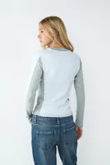 Remera de manga larga color blanco melange, con cuello redondo y diseño acanalado rib 2x2. Presenta un fit ajustado que acompaña la silueta.