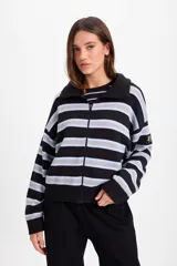 Campera de punto holgada con cuello tipo chomba y cierre frontal oculto. Presenta un diseño de rayas horizontales en tonos marrón, rojo y crema, con puños y ruedo acanalados. Incluye un parche bordado en la manga izquierda.