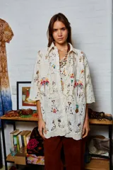 Camisa holgada color crema con bordados de palmeras y frutos, confeccionada en algodón. Presenta terminación de puntilla en el ruedo.